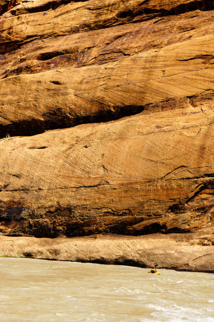 Big, slickrock walls dwarf Justin Jimenez as he paddles the high flow release on the Dolores.